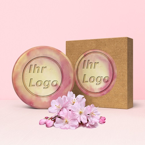 Runde, marmorierte Handseife mit Ihrem Logo, neben passender Verpackung und Kirschblüten arrangiert.